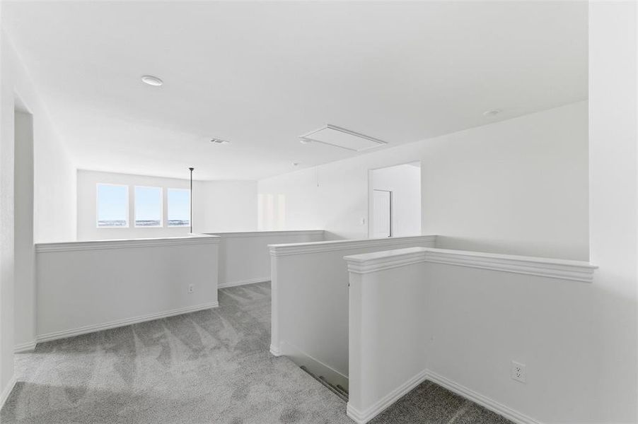 Hallway featuring light carpet, an upstairs landing, and attic access