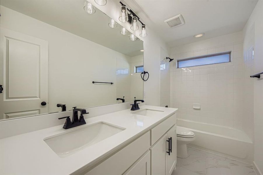 Bathroom with double vanity, tub / shower combination, light marble finish floors, and recessed lighting