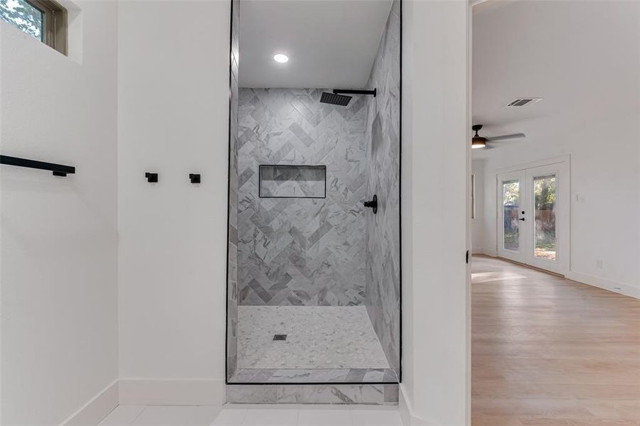 Bathroom featuring french doors, hardwood / wood-style flooring, ceiling fan, and tiled shower