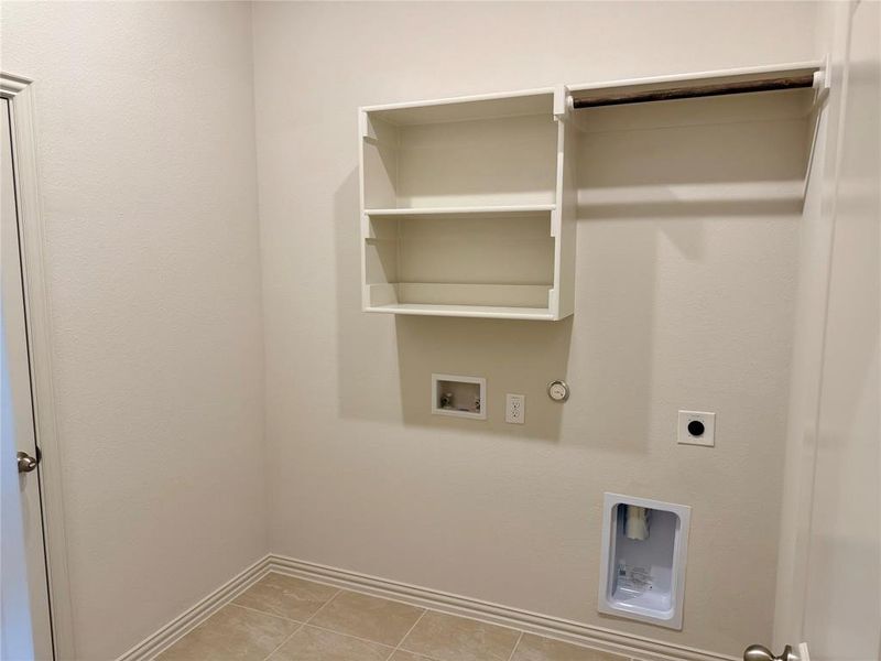 Utility room featuring neutral wall paint, tiled flooring, built-in shelving, and a hanging rod