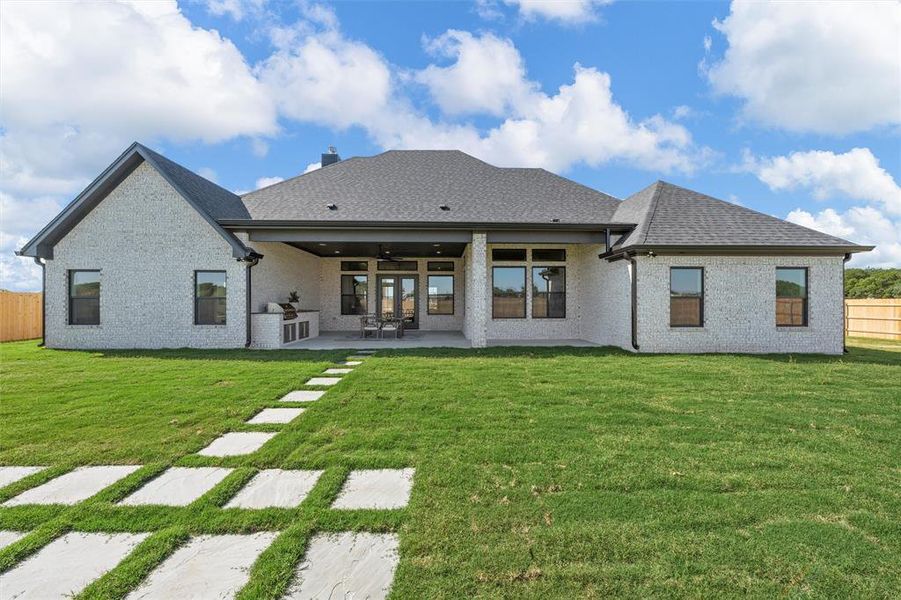 Rear view of house with a ceiling fan, a patio area, brick siding, and a shingled roof