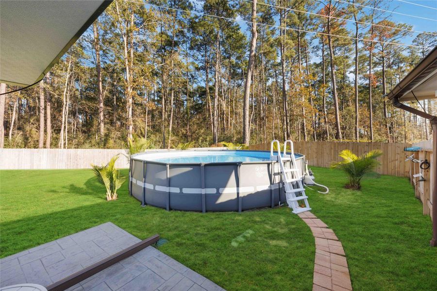 Above-Ground Pool & Backyard ViewEnjoy your own private retreat with an above-ground pool set against a tree-lined backdrop, offering both relaxation and summer fun. The pool is easily accessible from the covered patio and surrounded by a spacious, fully fenced yard with no rear neighbors, providing privacy and plenty of room for entertaining, play, or additional outdoor features. A perfect complement to the home’s exceptional outdoor living space. Above-Ground Pool & Backyard ViewEnjoy your own private retreat with an above-ground pool set against a tree-lined backdrop, offering both relaxation and summer fun. The pool is easily accessible from the covered patio and surrounded by a spacious, fully fenced yard with no rear neighbors, providing privacy and plenty of room for entertaining, play, or additional outdoor features. A perfect complement to the home’s exceptional outdoor living space.