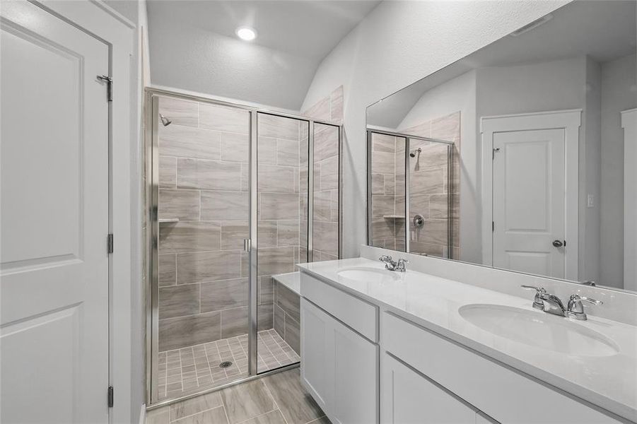 Full bathroom featuring a shower stall, double vanity, and wood finished floors Full bathroom featuring a shower stall, double vanity, and wood finished floors