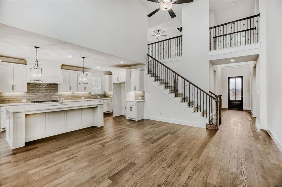 Unfurnished living room with light wood-style flooring, a high ceiling, a ceiling fan, and recessed lighting