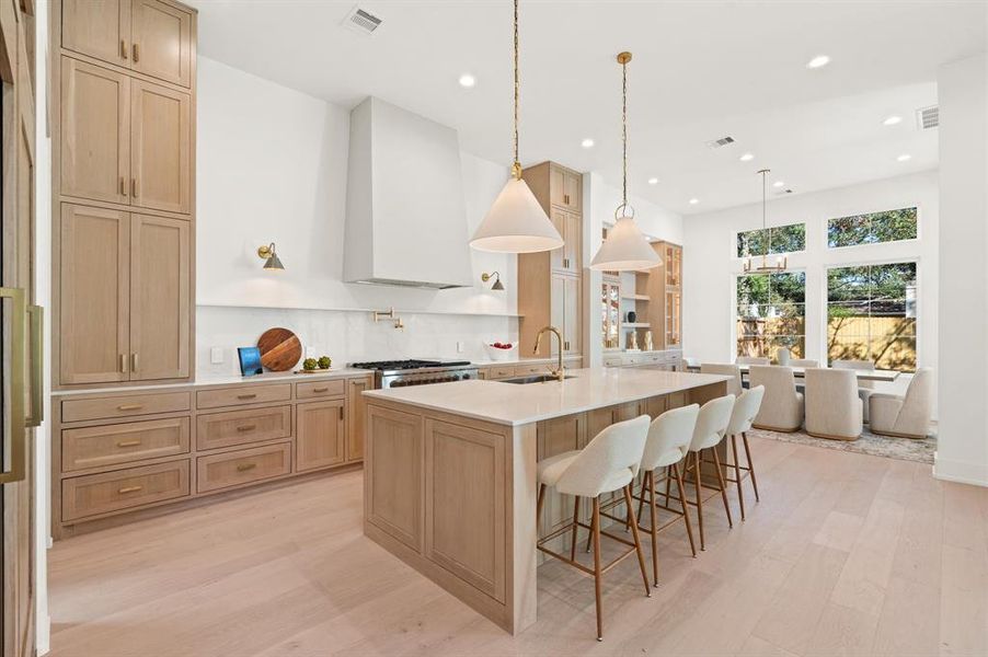 Open kitchen with custom white oak cabinets and flooring. Previous TOMO Homes project.