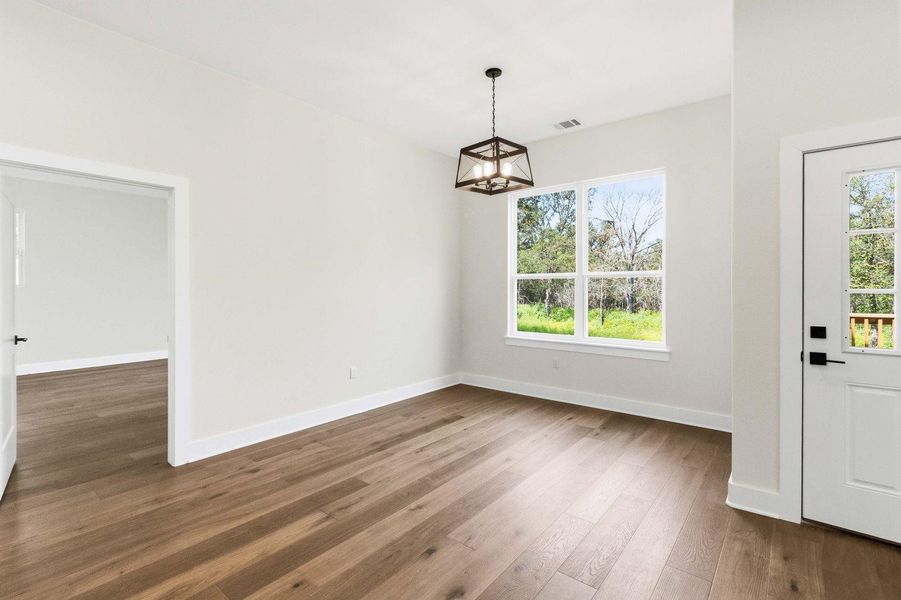 A well-lit room showcasing rich hardwood flooring and a charming chandelier, with abundant natural light from a large window. A well-lit room showcasing rich hardwood flooring and a charming chandelier, with abundant natural light from a large window.