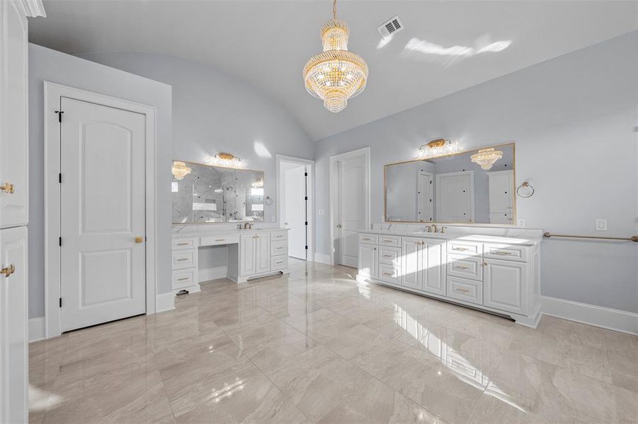 Bathroom featuring vaulted ceiling, two vanities, light marble finish floors, and a chandelier Bathroom featuring vaulted ceiling, two vanities, light marble finish floors, and a chandelier