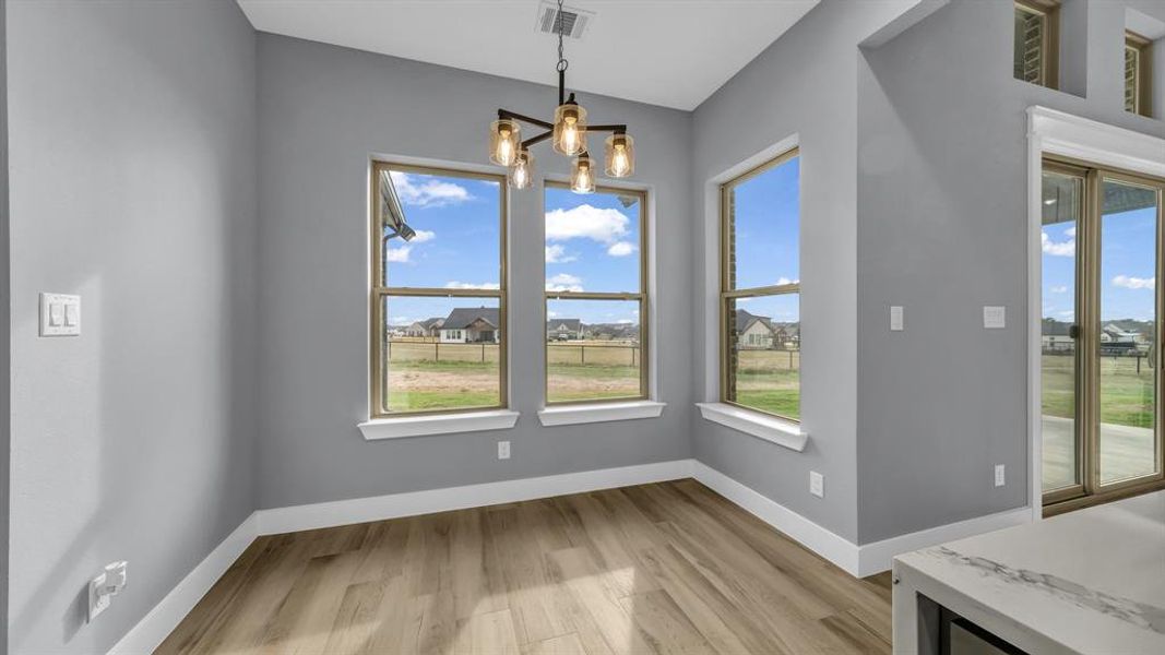 Unfurnished dining area with light wood-type flooring, a chandelier, and a residential view