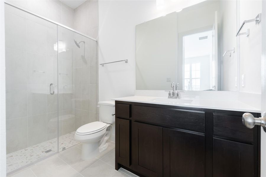 Full bath with vanity, a shower stall, and light tile patterned flooring