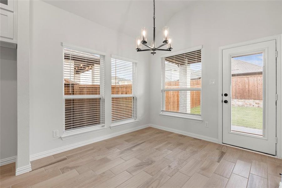 Unfurnished dining area featuring a notable chandelier, light hardwood / wood-style flooring, and lofted ceiling