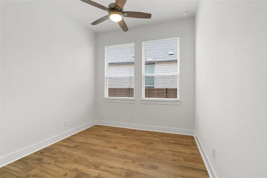 A quiet bedroom showcases durable wood flooring and a modern ceiling fan, offering a serene retreat. A quiet bedroom showcases durable wood flooring and a modern ceiling fan, offering a serene retreat.