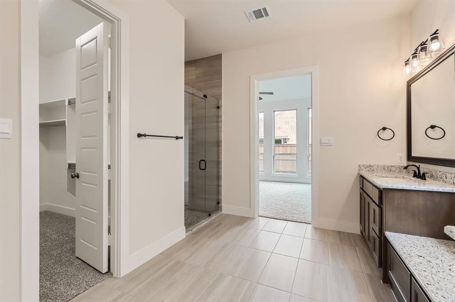 Bathroom featuring tile patterned flooring, vanity, and a shower with door