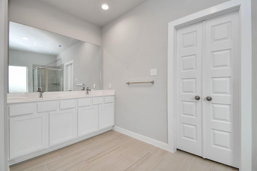 Experience luxury in this spa-like primary bathroom featuring a massive walk-in shower with tile surround. Light colored cabinets with light granite countertops complement the space, alongside a spacious walk-in closet with shelving, high ceilings, custom paint, and sleek, dark modern finishes. An ideal retreat for unwinding after a long day. Sample photo of completed home with similar floor plan. Actual colors and selections may vary. Experience luxury in this spa-like primary bathroom featuring a massive walk-in shower with tile surround. Light colored cabinets with light granite countertops complement the space, alongside a spacious walk-in closet with shelving, high ceilings, custom paint, and sleek, dark modern finishes. An ideal retreat for unwinding after a long day. Sample photo of completed home with similar floor plan. Actual colors and selections may vary.