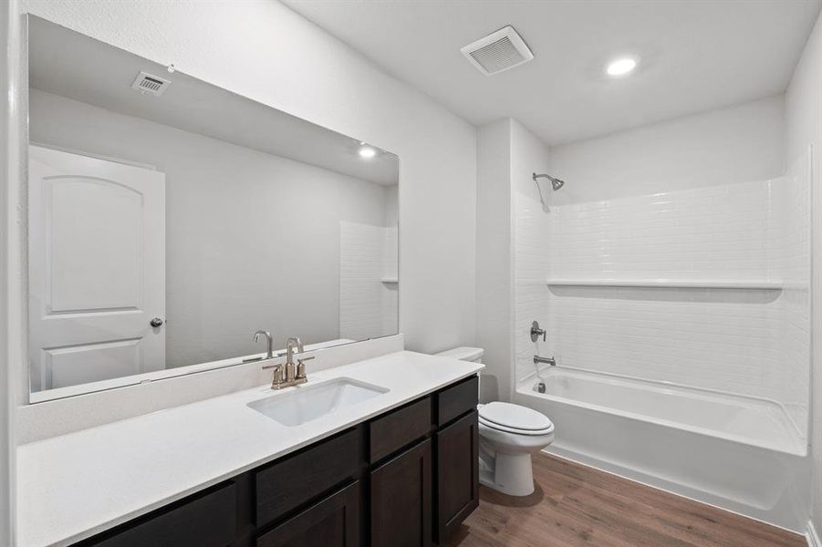 Full bathroom with visible vents, vanity, wood finished floors, toilet, and  shower combination