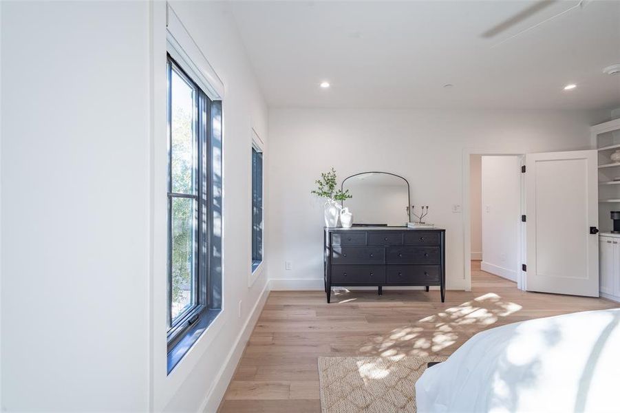 Bedroom with ceiling fan, multiple windows, and light wood-type flooring