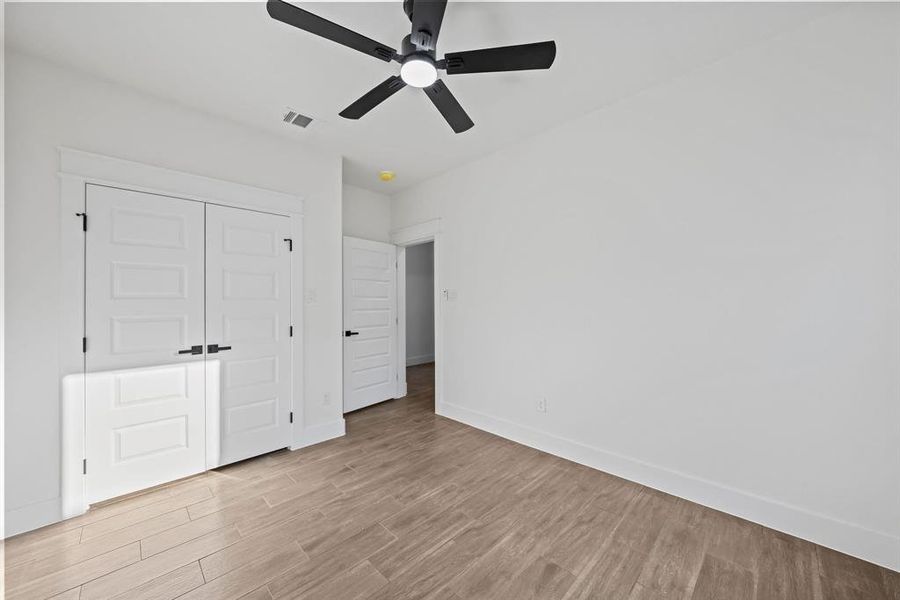 Unfurnished bedroom with light wood-type flooring, ceiling fan, and a closet