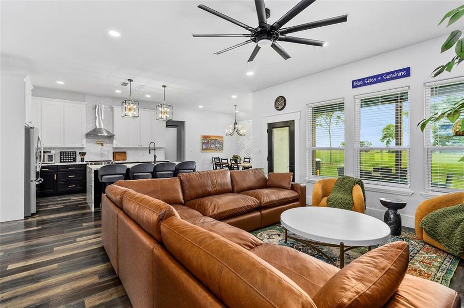 Cozy yet spacious living area with leather furniture looking to kitchen, dining, and back door