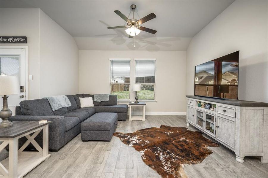 Living area featuring light wood-type flooring, lofted ceiling, baseboards, and ceiling fan