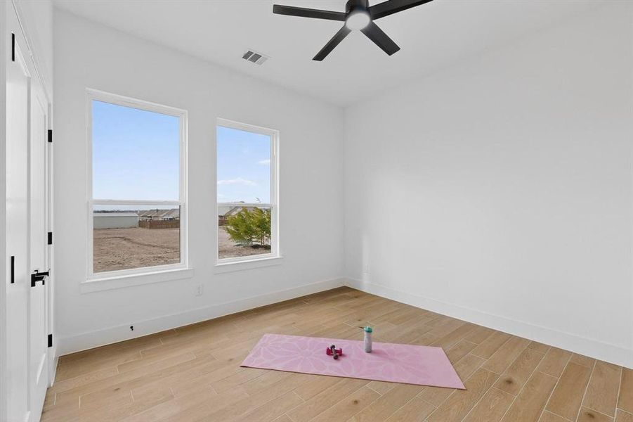 Exercise area with light wood-type flooring and a ceiling fan