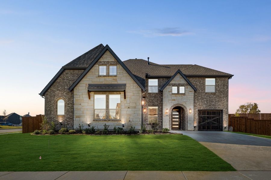 Two-story home with brick and stone exterior, arched entry, single-car garage, and manicured front lawn at dusk Two-story home with brick and stone exterior, arched entry, single-car garage, and manicured front lawn at dusk