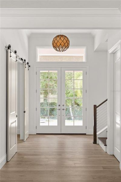 Foyer view showcasing the home's entry, featuring a double glass door, a decorative light fixture, and access to the office, stairwell, and storage closets.