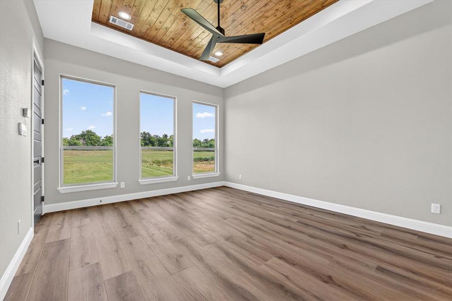 Spacious room featuring wood-finish flooring and three large windows