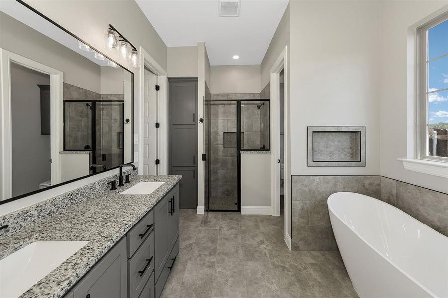 Full bathroom with a stall shower, a freestanding tub, double vanity, recessed lighting, and tile walls