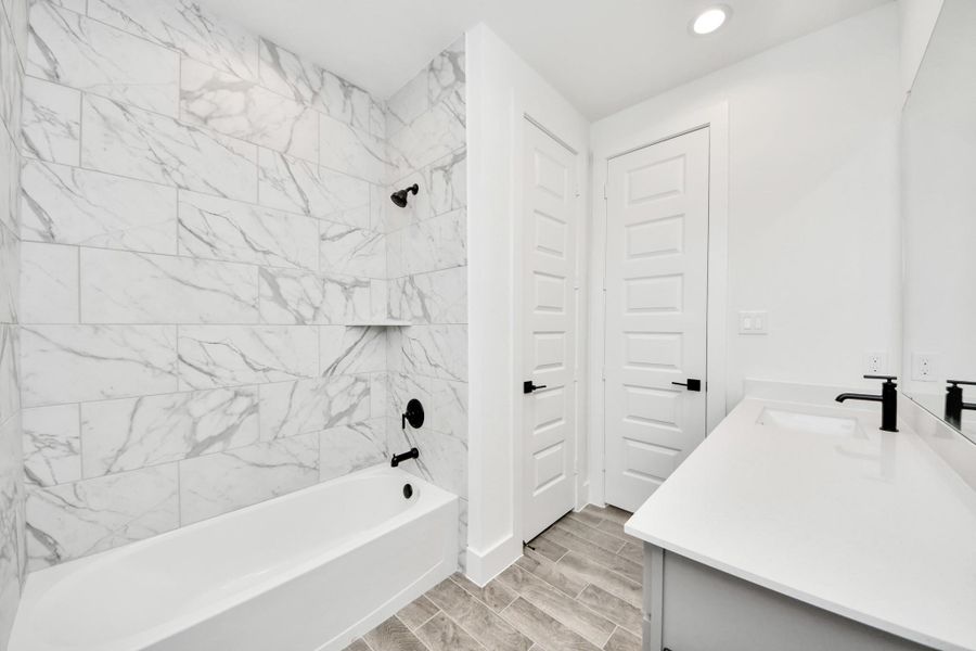 Secondary bath features tile flooring, bath/shower combo with tile surround, light stained wood cabinets, beautiful light countertop. Secondary bath features tile flooring, bath/shower combo with tile surround, light stained wood cabinets, beautiful light countertop.