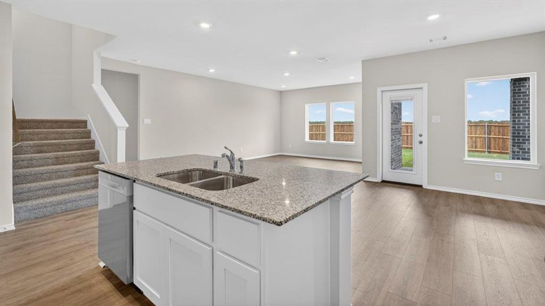 Kitchen island featuring a granite countertop, double basin sink, and integrated dishwasher