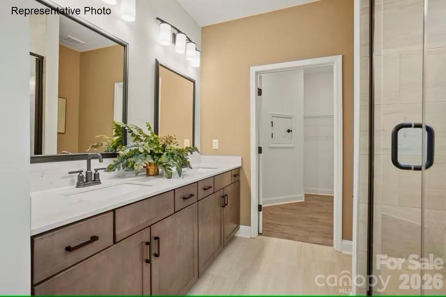 Primary bathroom includes dual vanities and walk-in shower with tiled bench seat