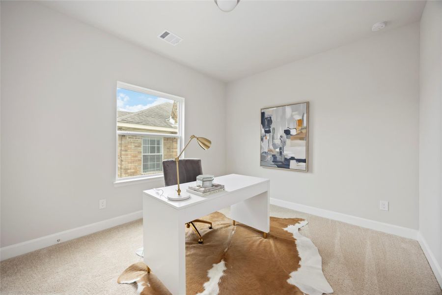 A secondary bedroom on the second floor presents a perfect blend of comfort and functionality, complete with a desk, window, and proximity to the shared hall bathroom.