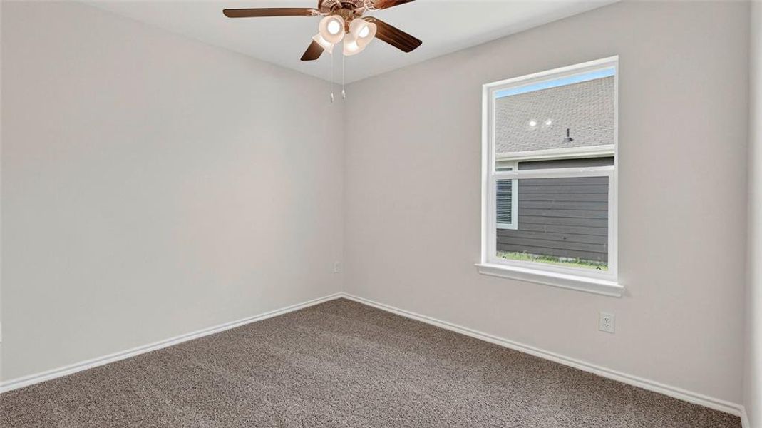 Carpeted room featuring a ceiling fan with light fixture, a single-pane window with white trim, and light-colored walls Carpeted room featuring a ceiling fan with light fixture, a single-pane window with white trim, and light-colored walls