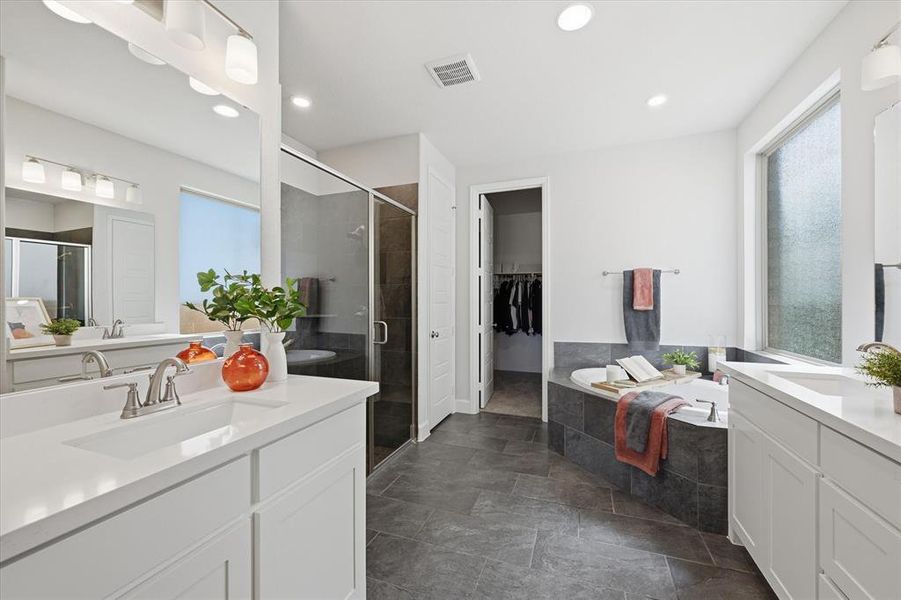 Primary bath with two vanities, a garden tub, a shower stall, and a spacious walk-in closet