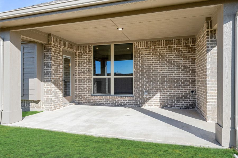 Covered back patio with concrete floor and brick exterior walls, adjacent to green lawn