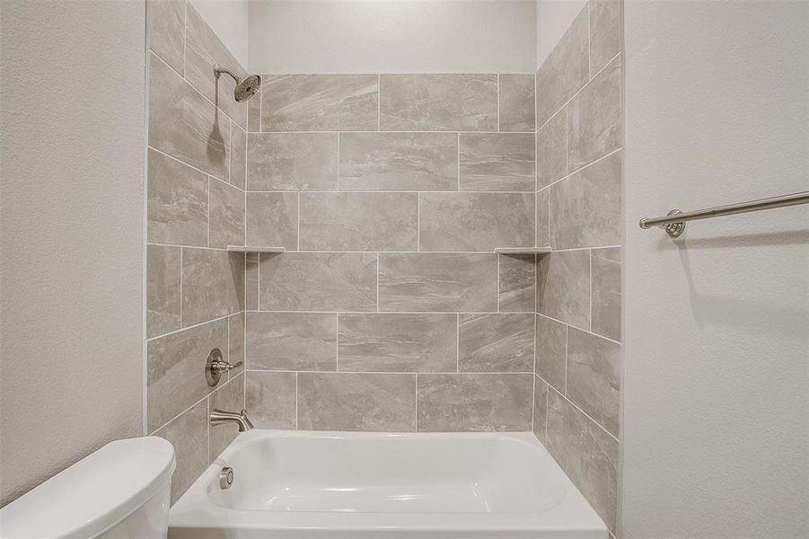 Bathroom featuring tiled shower / bath combo and toilet