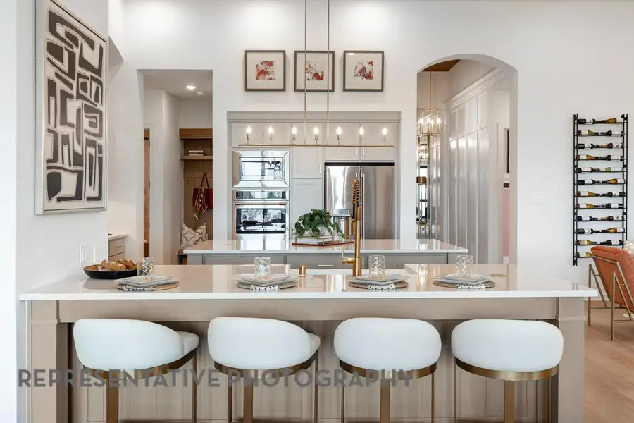 Bar with arched walkways, appliances with stainless steel finishes, pendant lighting, and light wood-style floors