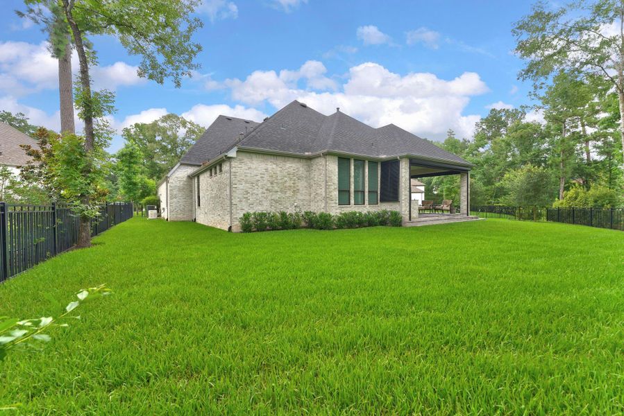 The rear and side yard showcase the depth of the lot and the privacy created by surrounding greenery. With generous green space and a premium lot position, the outdoor setting feels unusually open and serene.