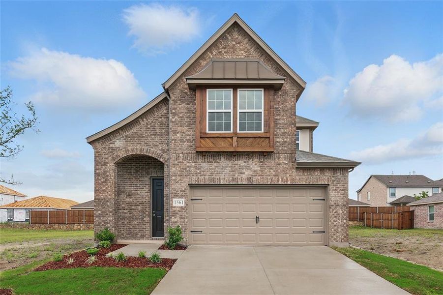 View of front facade with brick siding, concrete driveway, an attached garage, and a standing seam roof