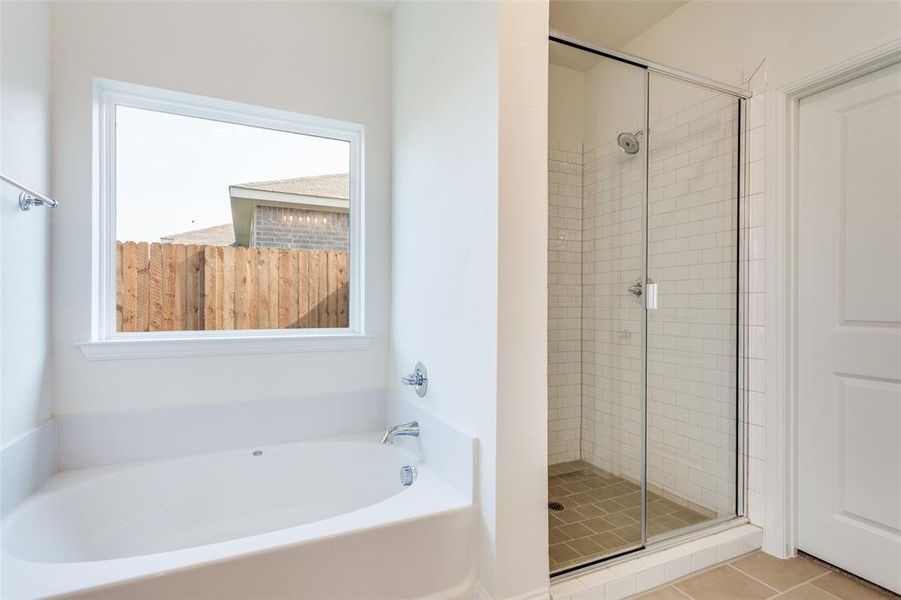 Bathroom with shower with separate bathtub and tile patterned floors