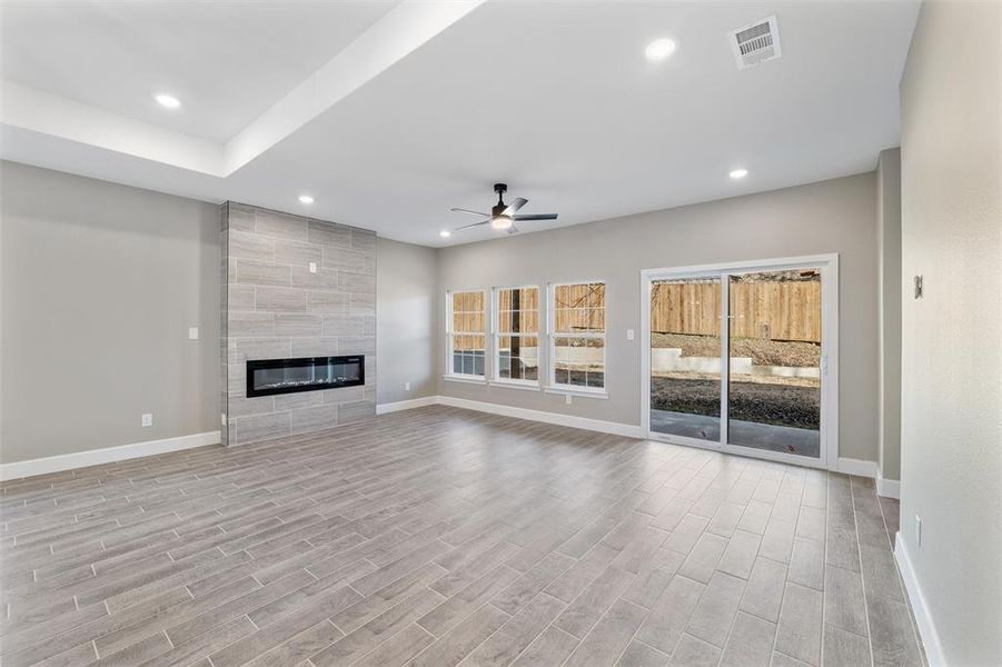 Unfurnished living room featuring ceiling fan, a fireplace, and light hardwood / wood-style flooring