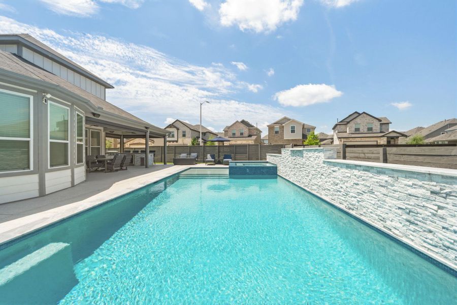 Private backyard oasis featuring a rectangular swimming pool with integrated spa and a stacked stone waterfall and bubbler feature wall