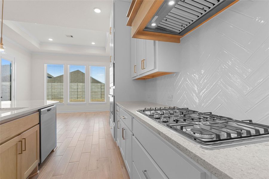 A closer look at the gourmet kitchen highlights the sleek gas cooktop, beautiful granite countertops, and stylish tile backsplash, designed for both everyday cooking and entertaining, all complemented by elegant finishes and thoughtful details throughout.