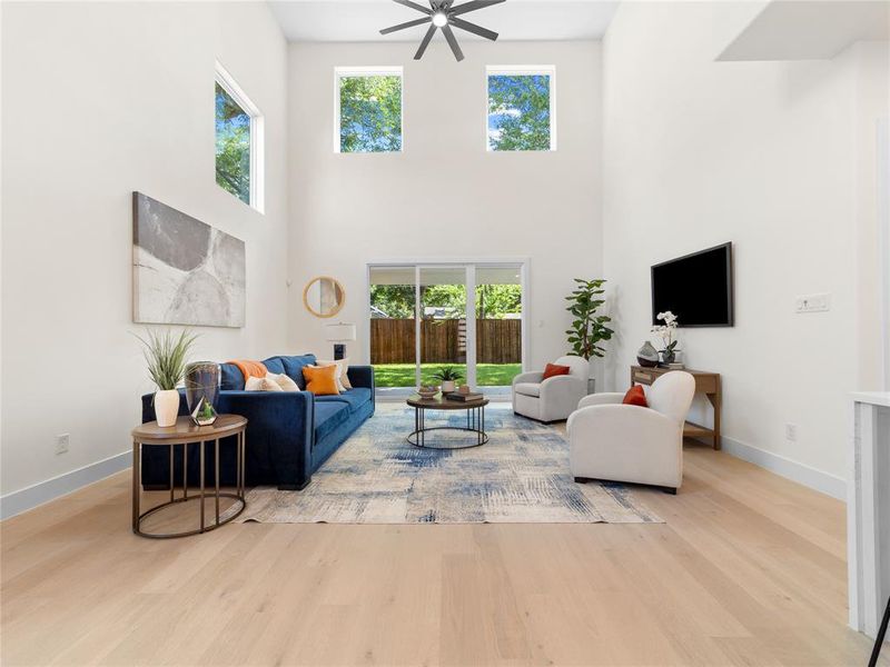 Living room with wood finished floors, a high ceiling, and ceiling fan