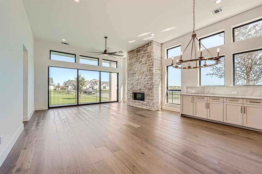 Unfurnished living room featuring ceiling fan with notable chandelier, light wood-type flooring, and a fireplace