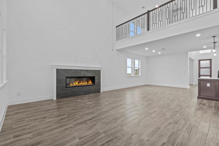 Unfurnished living room featuring a tiled fireplace and a towering ceiling