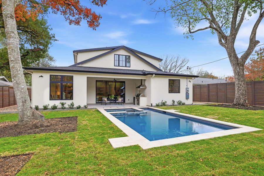 Rear view of property with a ceiling fan, a fenced backyard, stucco siding, and a pool with connected hot tub