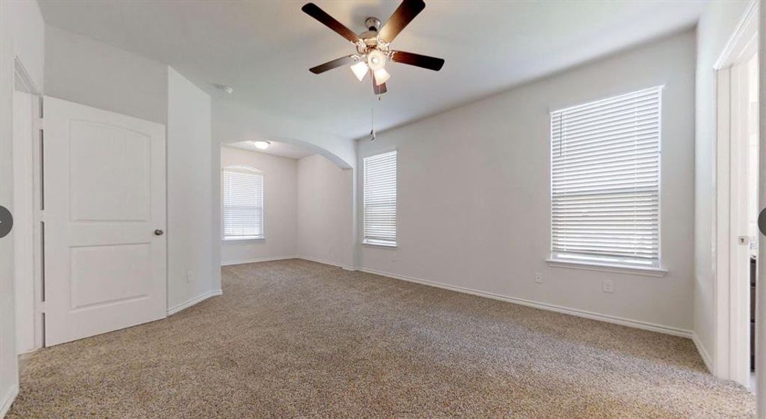 Spare room with ceiling fan, carpet flooring, baseboards, and arched walkways