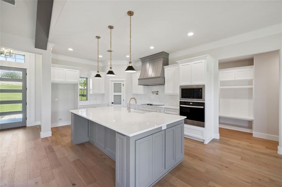 Kitchen with white cabinetry, tasteful backsplash, black appliances, and custom exhaust hood