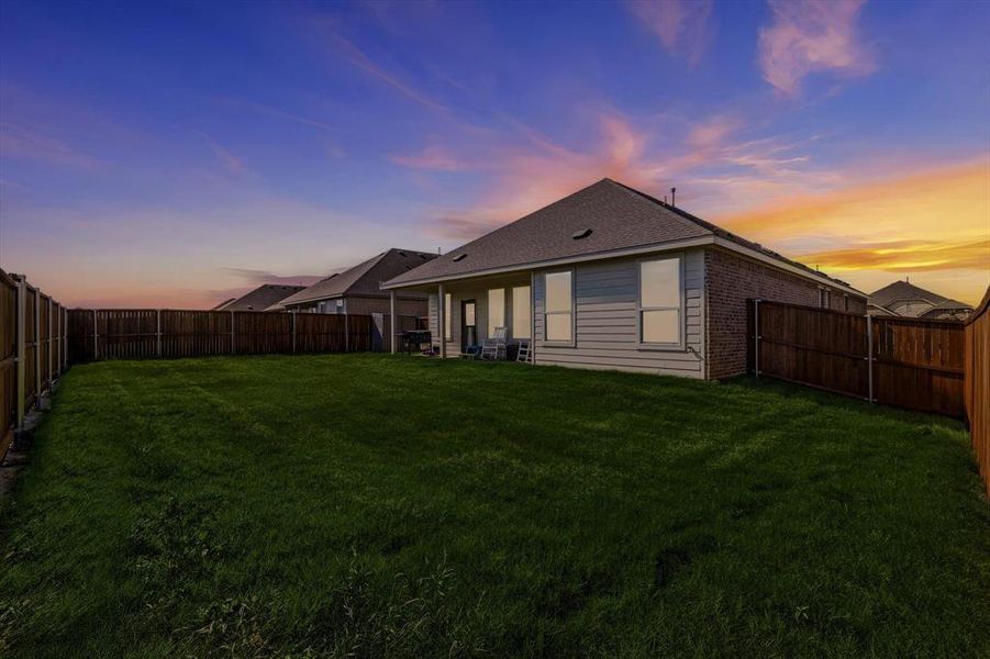 Expansive backyard featuring a manicured lawn, full perimeter privacy fencing, and an extended concrete patio Expansive backyard featuring a manicured lawn, full perimeter privacy fencing, and an extended concrete patio
