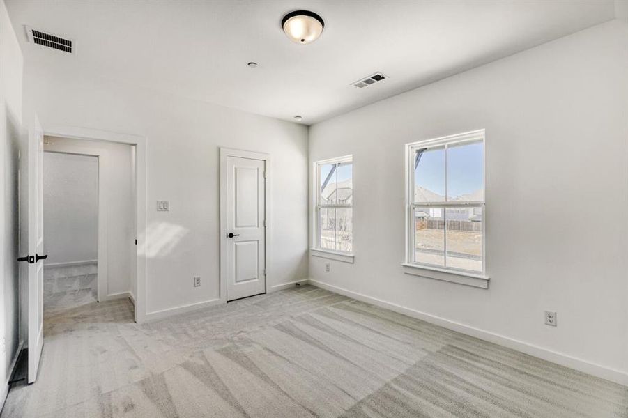 Unfurnished bedroom with light colored carpet and baseboards